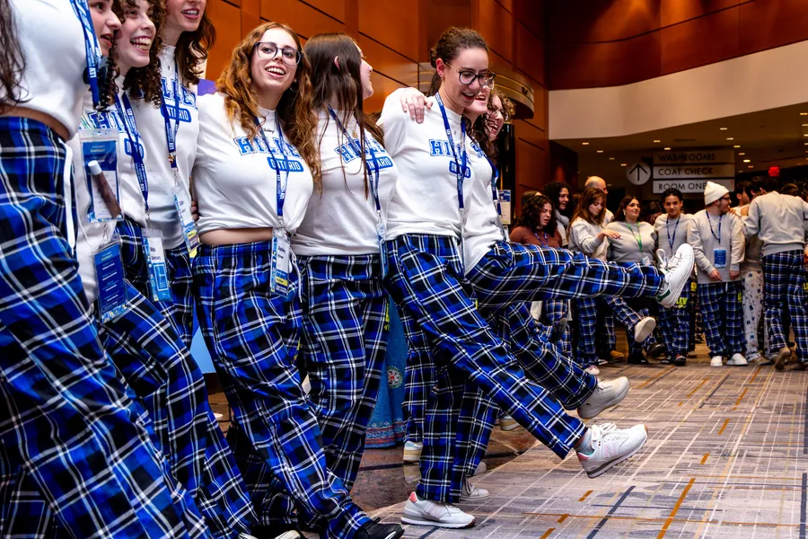 Students in a kick line, in LEV plaid.