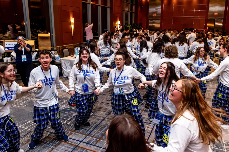 Students dancing in a circle, holding hands.