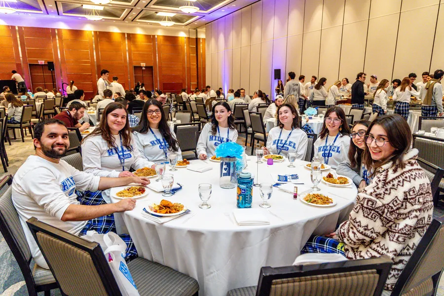 A dinner table of students turning to smile at the camera.