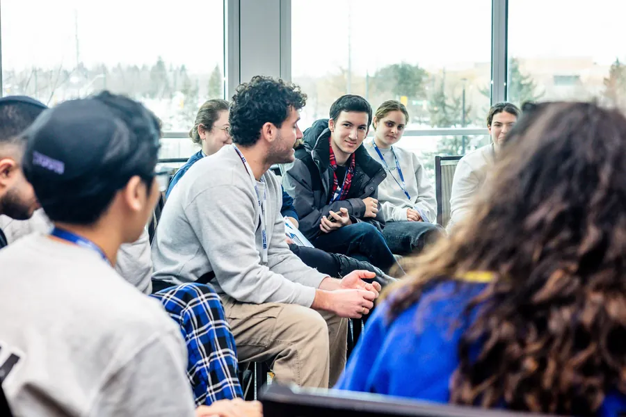 Students in a circle, listening to one of their own speak.