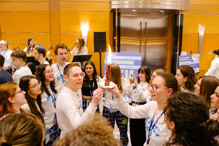 Havdalah: a braided candle held up, alight, in a crowd of students.