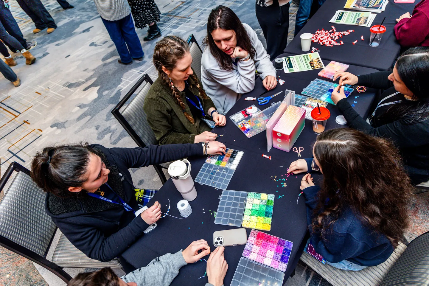 Students around a table covered in trays of coloured beads, seen from above.